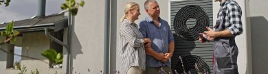 3 Personen vor einem Haus / Ehepaar und Techniker